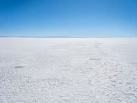 footprints are in the sand on the shore of a lake or water, making the shape of a heart