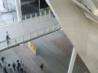 a group of people walking over an airport walkway under a building with columns and pillars
