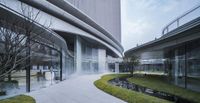 a very tall building with a waterfall running down the side of it near green plants