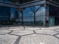 hexagon shaped mosaic pattern in front of glass - covered building, with trees reflecting in window