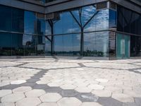 hexagon shaped mosaic pattern in front of glass - covered building, with trees reflecting in window