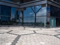 hexagon shaped mosaic pattern in front of glass - covered building, with trees reflecting in window