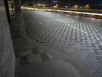 a parking lot with traffic in the dark and lights shining on the ground and buildings