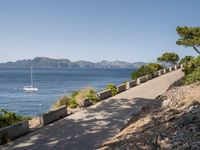 path along the sea, showing boat, and beach views from an overlook, in front of mountains