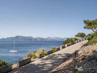 path along the sea, showing boat, and beach views from an overlook, in front of mountains