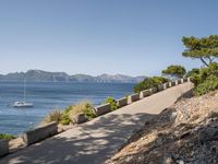 path along the sea, showing boat, and beach views from an overlook, in front of mountains