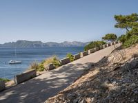 path along the sea, showing boat, and beach views from an overlook, in front of mountains