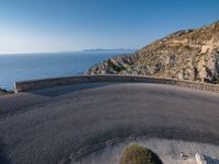 a road going up a mountain near the ocean with a ramp for bikes to make it easier to cross the roadway