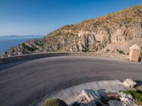 a road going up a mountain near the ocean with a ramp for bikes to make it easier to cross the roadway