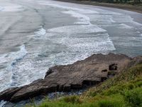 a few people are surfing and in the water near rocks, near the shore line