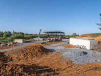 a picture of a building being built on a field near a forest in the background