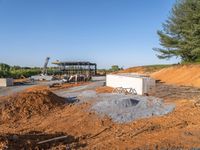 a picture of a building being built on a field near a forest in the background