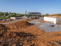 a picture of a building being built on a field near a forest in the background