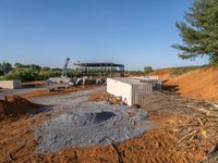 a picture of a building being built on a field near a forest in the background