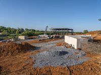 a picture of a building being built on a field near a forest in the background