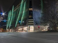 a road with a building that has glass walls at one side and lights on the other side