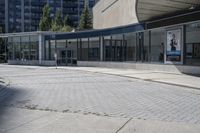 a person sitting at the bench in front of a mall that is empty of people