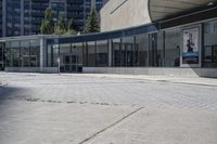 a person sitting at the bench in front of a mall that is empty of people