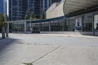 a person sitting at the bench in front of a mall that is empty of people