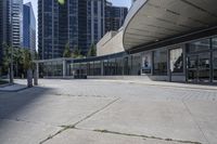 a person sitting at the bench in front of a mall that is empty of people