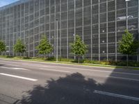 the building is built with glass and steel netting in front of it on a street