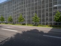 the building is built with glass and steel netting in front of it on a street