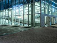 a modern office building with large windows in the front of it at night, next to a bench