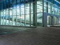 a modern office building with large windows in the front of it at night, next to a bench