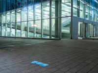 a modern office building with large windows in the front of it at night, next to a bench