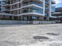 an empty parking lot with a building behind it, with an apartment building to the left