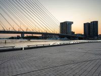 the skyline in the city is filled with tall buildings and bridges by the water and a man standing near a bench on the sidewalk