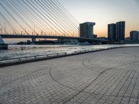 the skyline in the city is filled with tall buildings and bridges by the water and a man standing near a bench on the sidewalk