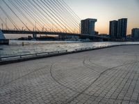 the skyline in the city is filled with tall buildings and bridges by the water and a man standing near a bench on the sidewalk