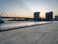 the skyline in the city is filled with tall buildings and bridges by the water and a man standing near a bench on the sidewalk