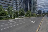 the road in front of a big building that is surrounded by tall buildings and a very nice