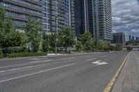 the road in front of a big building that is surrounded by tall buildings and a very nice