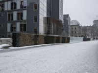 a person that is walking down the street in the snow on the street near some buildings