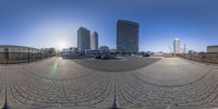 a wide angle fish eye view shows the buildings behind a busy street and a parking lot