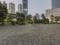 a paved pathway in a public plaza in a city at night, surrounded by high - rise buildings