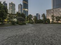 a paved pathway in a public plaza in a city at night, surrounded by high - rise buildings