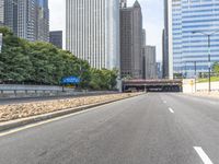 an empty street in front of some very high rise buildings, and there's also a railroad with a train on the track