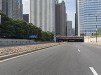 an empty street in front of some very high rise buildings, and there's also a railroad with a train on the track