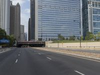 an empty street in front of some very high rise buildings, and there's also a railroad with a train on the track