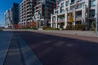 a street that is next to some tall buildings and a red fire hydrant in the middle of the road