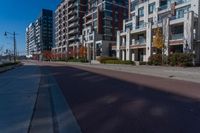 a street that is next to some tall buildings and a red fire hydrant in the middle of the road