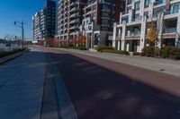 a street that is next to some tall buildings and a red fire hydrant in the middle of the road