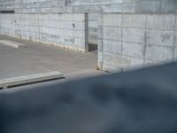 the empty parking lot in front of a wall with apartment buildings on it and a skateboarder on a ramp