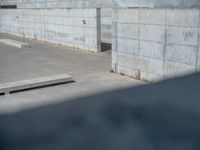 the empty parking lot in front of a wall with apartment buildings on it and a skateboarder on a ramp