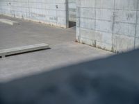 the empty parking lot in front of a wall with apartment buildings on it and a skateboarder on a ramp