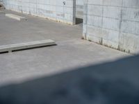 the empty parking lot in front of a wall with apartment buildings on it and a skateboarder on a ramp